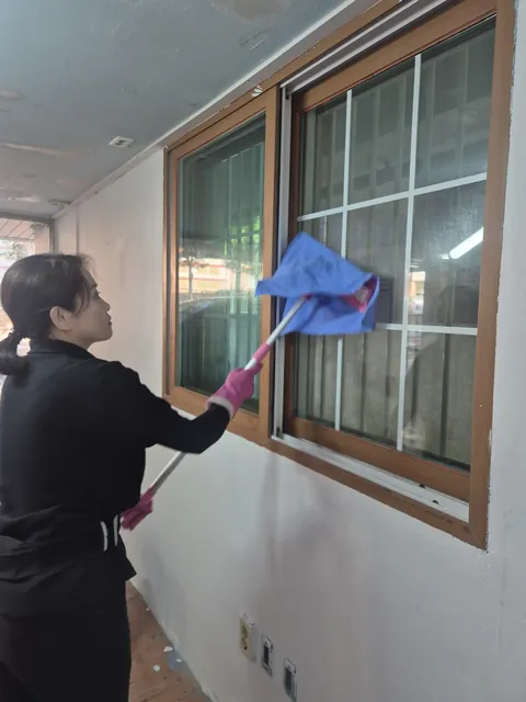 사무실이전철거 원상복구 창문과 창틀을 닦아 마감 상태를 정리하는 작업자